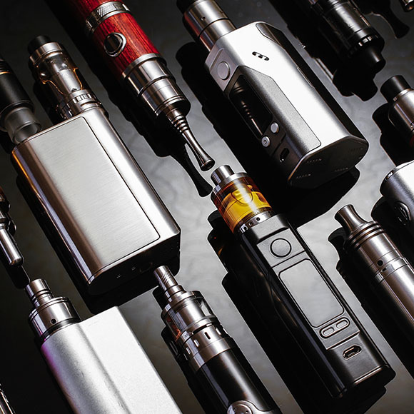 various vaping devices arranged on a reflective surface showcasing modern vape technology and e-cigarette options for enthusiasts